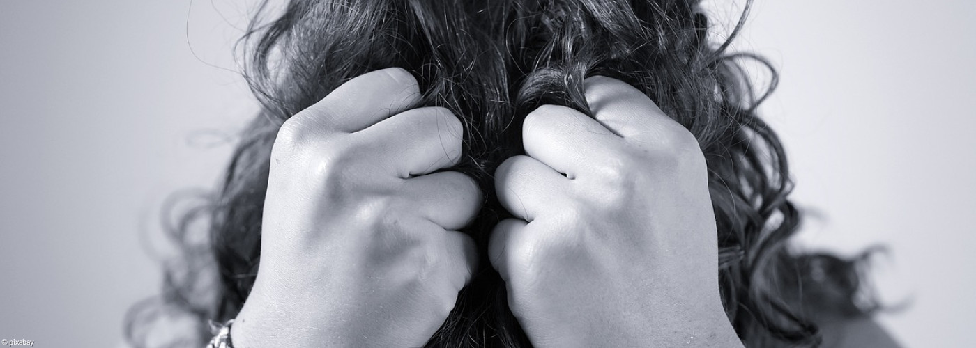 Verzweifelte Frau, die ihr gesicht hinter geballten Fäusten versteckt