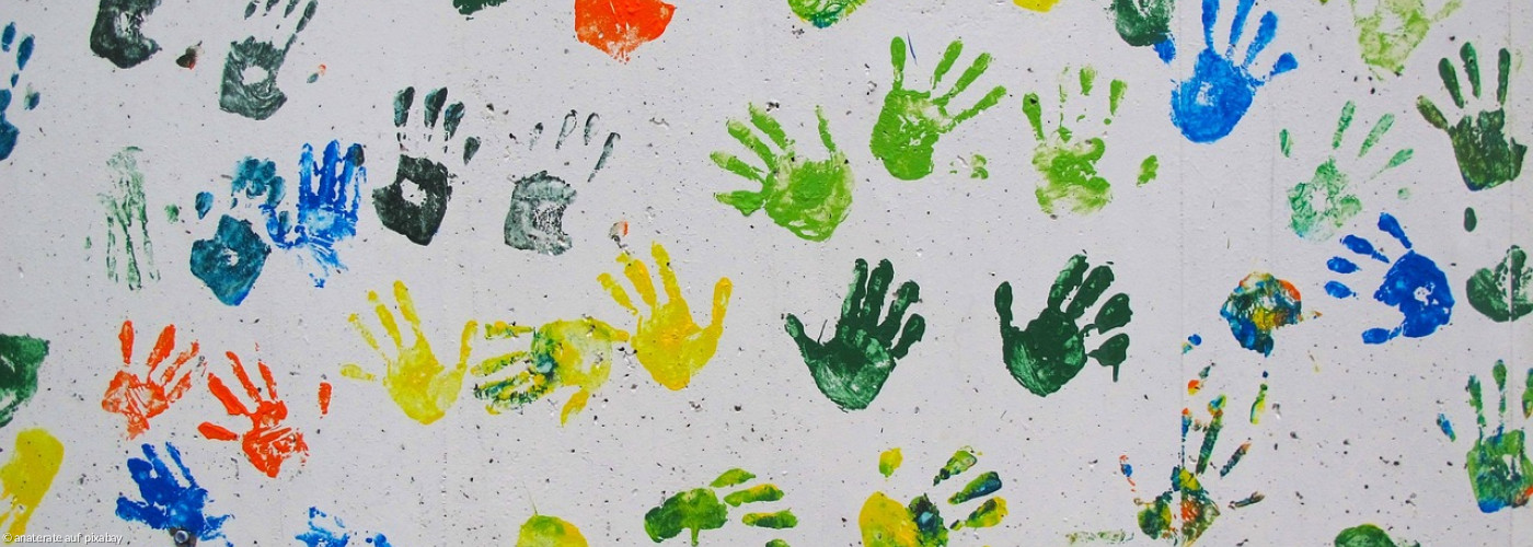 bunte Handabdrücke von Kindern auf weißer Wand