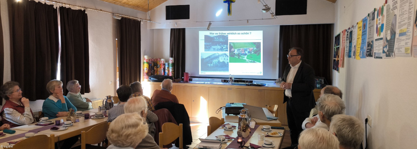 Foto vom Kaffeenachmittag: ältere Menschen folgen einem Vortrag im Gemeinderaum