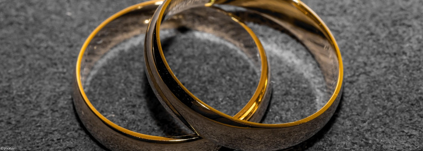 2 goldene Eheringe liegen versetzt übereinander