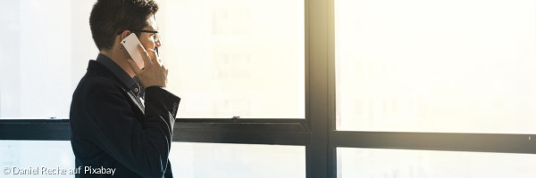 Mann telefoniert vor großem Fenster