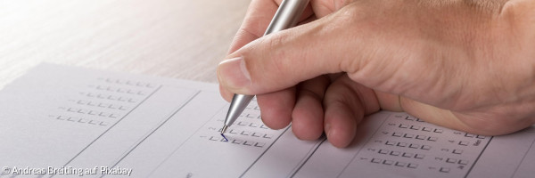Eine Hand mit Stift in der Hand füllt ein Formular aus
