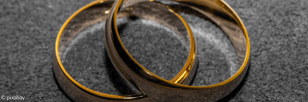 2 goldene Eheringe liegen versetzt übereinander
