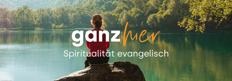 Frau sitzt auf einem Stein vor einem See, im Vordergrund steht "ganzhier" Spiritualität evangelisch