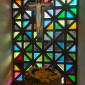 Taufbecken mit Kreuz und bunten Fenstern im Hintergrund