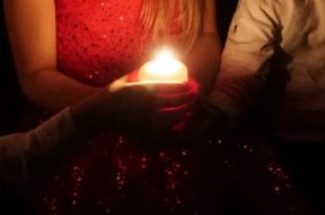 3 Kinder halten eine brennende Kerze